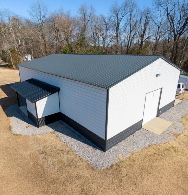 White barn with a dark roof and an attached lean-to